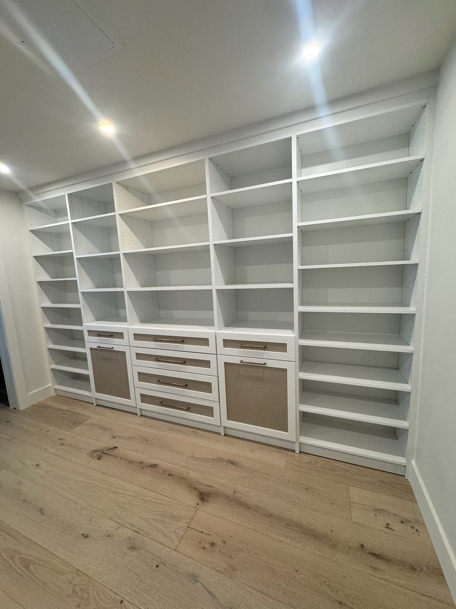 Floor to ceiling built in wall unit with shaker fronts, hamper pullouts and brass hardware